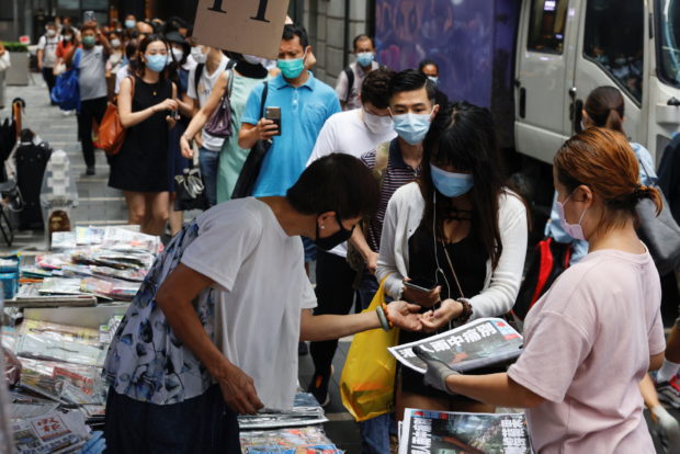 People queue to buy copies of the final edition of Apple Daily, published by Next Digital, in the Central financial district, in Hong Kong