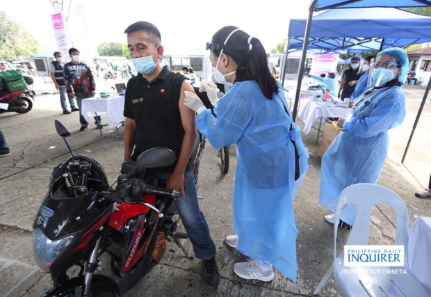 Man on motorbike gets inoculated at Vaccine Express. STORY: PH climbs to 33rd spot in COVID management