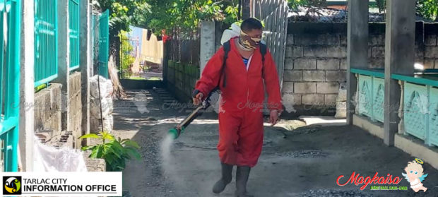 A local government employee disinfects a residential area in Tarlac City