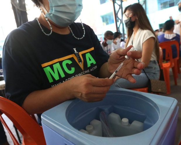 NO LETUP A health worker on Sunday prepares doses of Pfizer COVID-19 vaccine for hundreds of residents at Emilio Jacinto Elementary School in Tondo, Manila. —MARIANNE BERMUDEZ
