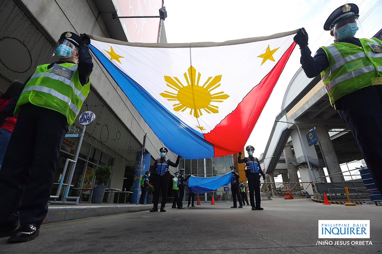 PHOTO: Cops carrying Philippine flag during a parade. STORY: Law needed to mandate use of Bagong Pilipinas hymn – Pimentel