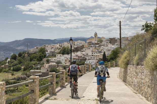 Mountainbiker approaching village at Andalucian Sierra Nevada, Spain