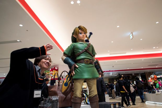 A man poses next to the Link, a game character for Nintendo's "The Legend of Zelda", at a new Nintendo store during a press preview in Tokyo on November 19, 2019. - Nintendo opens the doors this week at its first brick-and-mortar store in Tokyo, offering everything from Super Mario mugs to Zelda handbags at a complex targeting visiting gamers and local enthusiasts. 