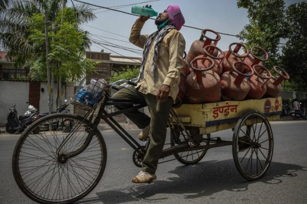 A Liquid Petroleum Gas (LPG) cylinder delivery man drinks water from a bottle during his shift on a hot summer afternoon in Amritsar on July 2, 2021.