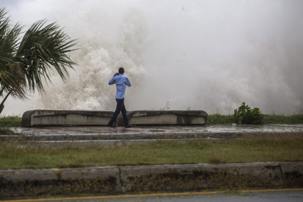 A man records a video of the strong waves during the passage of storm Elsa at the Malecón in Santo Domingo, on July 3, 2021. (Photo by Erika SANTELICES / AFP)