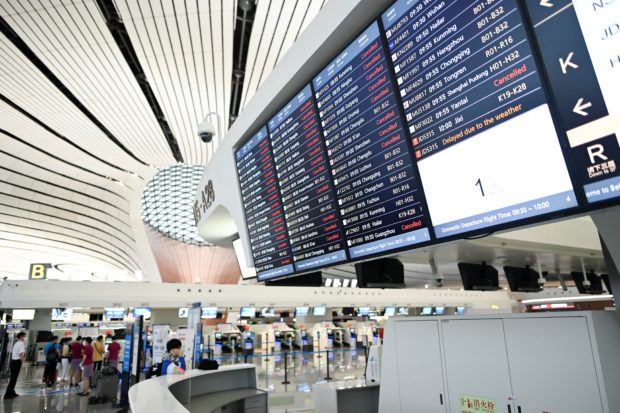 The departures board lists cancelled flights in red at Beijing's Daxing International Airport on July 12, 2021, as hundreds of flights were cancelled in the capital due to torrential downpours and gale-force winds. 