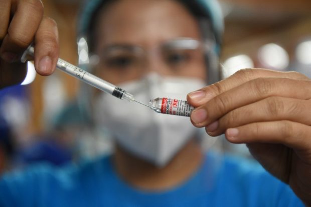 A health worker prepares a dose of Gamaleya National Center of Epidemiology and Microbiology's Sputnik V Covid-19 vaccine during a vaccination for residents in Mandaluyong City, suburban Manila on July 15, 2021. (Photo by Ted ALJIBE / AFP)