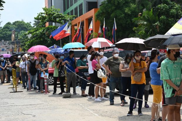 Residents queue up at a Covid-19 coronavirus vaccination centre in Mandaluyong City, suburban Manila on July 15, 2021. (Photo by Ted ALJIBE / AFP)