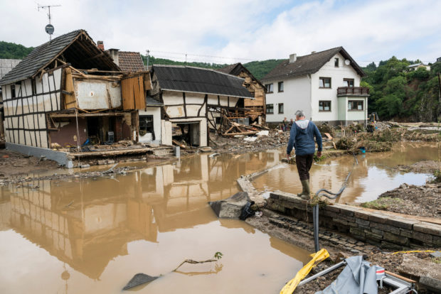 A man walks through the floods towards destroyed houses in Schuld near Bad Neuenahr, western Germany, on July 15, 2021. - Heavy rains and floods lashing western Europe have killed at least 42 people in Germany and left many more missing, as rising waters led several houses to collapse. 