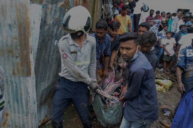 Rescue team personnel carry a body from the site of the landslide in a slum area where 18 people were killed after several homes were crushed by a collapsed wall and a landslide triggered by heavy monsoon rains in Mumbai on July 18, 2021. 