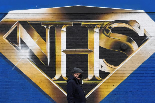  A man wearing a protective face mask walks past a mural praising the NHS (National Health Service) amidst the continuation of the coronavirus disease (COVID-19) pandemic, London, Britain, March 5, 2021. REUTERS/Toby Melville