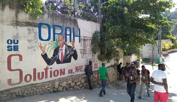 People walk past a wall with a mural depicting Haiti's President Jovenel Moise, after he was shot dead by unidentified attackers in his private residence, in Port-au-Prince, Haiti July 7, 2021. REUTERS/Robenson Sanon