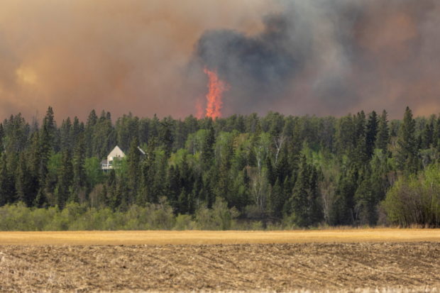 Wildfires burn near a house as the city of Prince Albert declared a state of emergency over a fast-moving wildfire, prompting some residents to evacuate, in Prince Albert, Saskatchewan, Canada May 18, 2021.