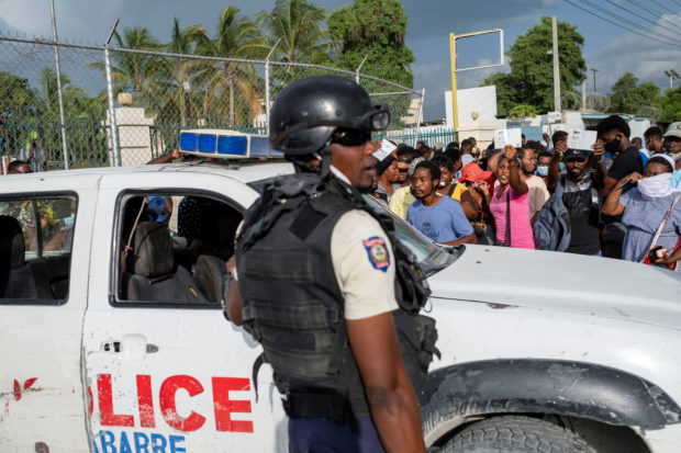 Haitian National Policemen guard the entrance to the U.S. Embassy as people gather to ask for asylum following the assassination of President Jovenel Moise