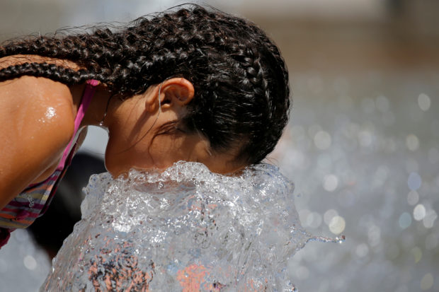 A child cools off in a fountain as a summer heatwave with high temperatures continues in Paris, France, August 3, 2018. REUTERS/Regis Duvignau