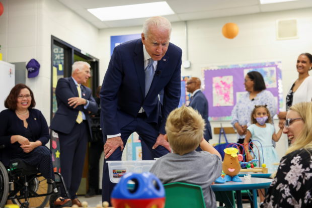 U.S. President Joe Biden flanked by President of McHenry County College Clint Gabbard and Senator Tammy Duckworth, speaks with a child, as he tours the Children's Learning Center at McHenry County College during a visit to the northwest Chicago suburb Crystal Lake, Illinois, U.S., July 7, 2021.