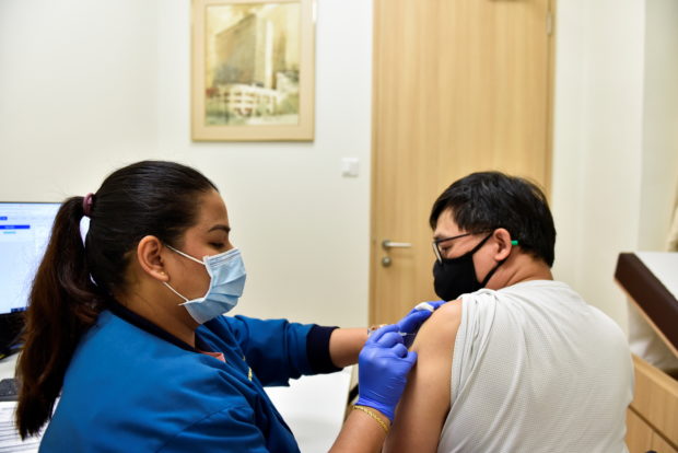 Nurl Anisah, a nurse at StarMed Specialist Centre, administers the Sinovac vaccine to Mr K.H Woon, 55, in Singapore
