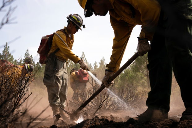 Firefighters extinguish hotspots in an area hit hard by the Bootleg Fire near Bly Oregon, U.S., July 19, 2021.  REUTERS/David Ryder
