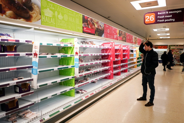 A man stands next to shelves empty of fresh meat in a supermarket, as the number of worldwide coronavirus cases continues to grow,  in London