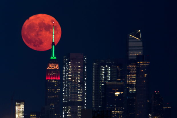 The full moon rises behind the Empire State Building in New York City, New York, U.S., July 23, 2021. REUTERS