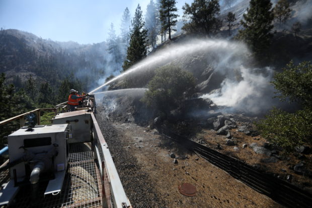 Firefighters assigned to the Union Pacific Fire Train protect the tracks and hinder the Dixie Fire from crossing the North Fork of the Feather River in Plumas National Forest, California, U.S., July 17, 2021.  