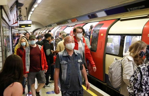 People wearing protective face masks walk along a platform on the London Underground, amid the coronavirus disease (COVID-19) outbreak, in London
