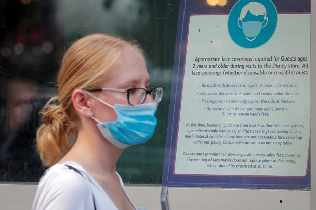 A woman wears a mask against the coronavirus disease (COVID-19), following the CDC recommendation that fully vaccinated Americans wear masks as the highly transmissible Delta variant has led to a surge in infections, as she enters the Disney Store in Times Square in New York City, New York, U.S., July 27, 2021. 