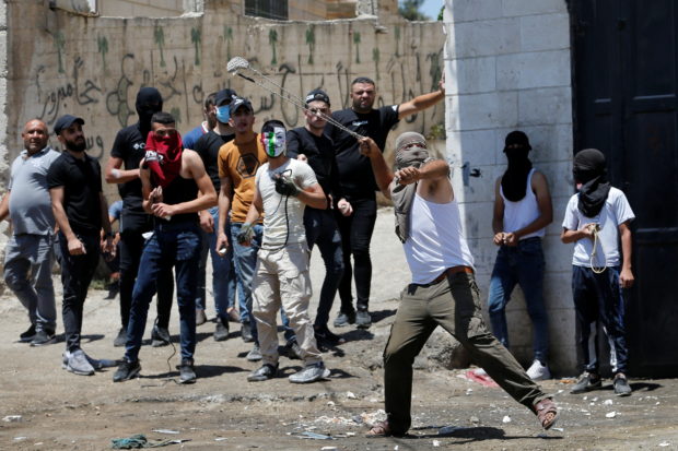 Palestinians hurl stones during the funeral of 12-year-old Palestinian boy Mohammad Al Alami, who was killed by Israeli troops, according to the Palestinian health ministry, near Hebron in the Israeli-occupied West Bank July 29, 2021. 