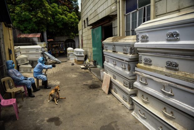 (FILE) Workers in protective suits, used due to the COVID-19 coronavirus outbreak, wait outside a crematorium facility as the cremation process takes some two hours in Manila on April 29, 2020. (Photo by Maria TAN / AFP)