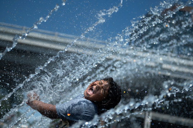 Micaela Montelara plays in the fountain at Georgetown Waterfront Park during a heatwave on August 13, 2021, in Washington, DC. - July was the hottest month ever recorded, according to data released, by the National Oceanic and Atmospheric Administration (NOAA)  on August 13, 2021. The combined land- and ocean-surface temperature around the world, according to NOAA, was 1.67 degrees Fahrenheit (0.93°C) above the 20th century average of 60.4F (15.7°C) since record-keeping started 142 years ago. 