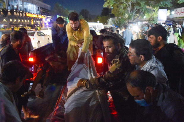 Volunteers and medical staff unload bodies from a pickup truck outside a hospital after two powerful explosions, which killed at least six people, outside the airport in Kabul on August 26, 2021. (Photo by Wakil KOHSAR / AFP)