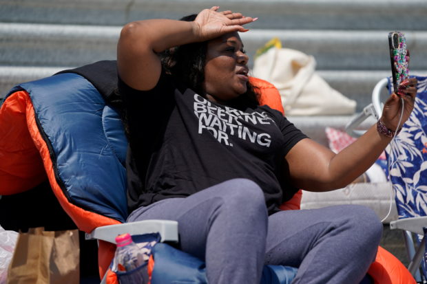 U.S. Representative Cori Bush (D-MO) holds up her phone while live streaming from the chair she spent the night in to highlight the upcoming expiration of the pandemic-related federal moratorium on residential evictions on the steps of the U.S. Capitol in Washington, DC.