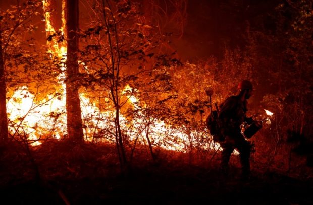 Forest Service firefighter Ben Foley lights backfires to slow the spread of the Dixie Fire, a wildfire near the town of Greenville, California, U.S. August 6, 2021. REUTERS/Fred Greaves