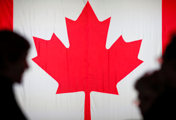 People are silhouetted in front of the Canadian national flag at the Palais des Congres in Montreal, Quebec, Canada 