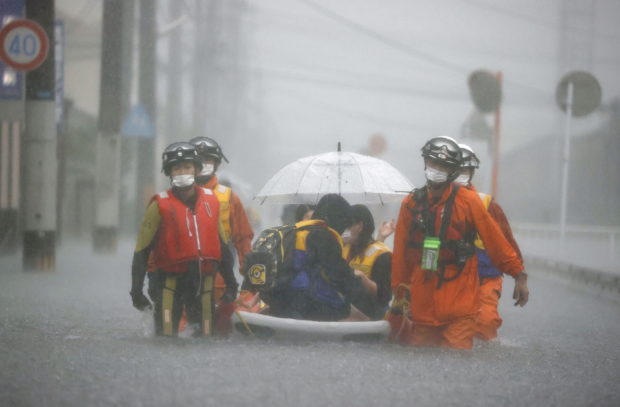 Firefighters transport stranded residents on a boat in a road flooded by heavy rain in Kurume, Fukuoka prefecture, western Japan, August 14, 2021, in this photo taken by Kyodo.  