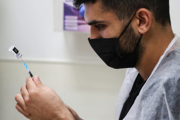 A medical worker prepares to administer a patient's third dose of the coronavirus disease (COVID-19) vaccine as country launches booster shots for over 40-year-olds, in Jerusalem August 20, 2021. REUTERS/Ammar Awad