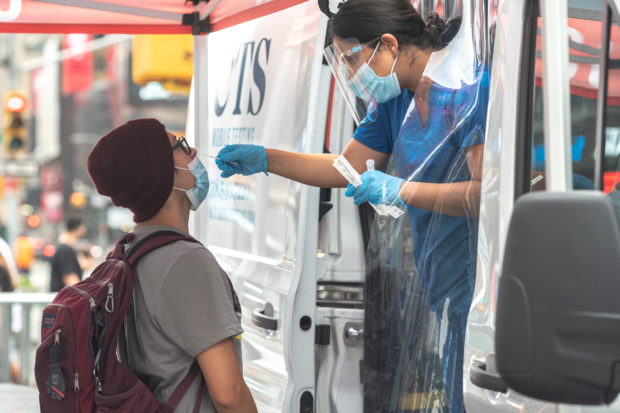 A person has a nasal swab applied for the coronavirus disease (COVID-19) test taken at a mobile testing site in Times Square in New York City