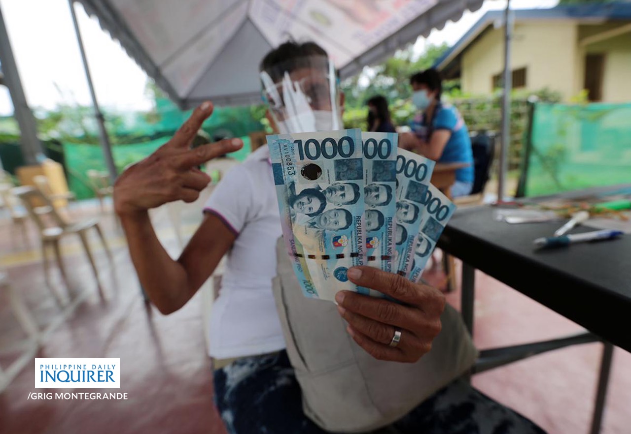 Residents receive cash aid thru the government's Social Amelioration Program (SAP) at the Lupang Pangako Covered Court in Quezon City
