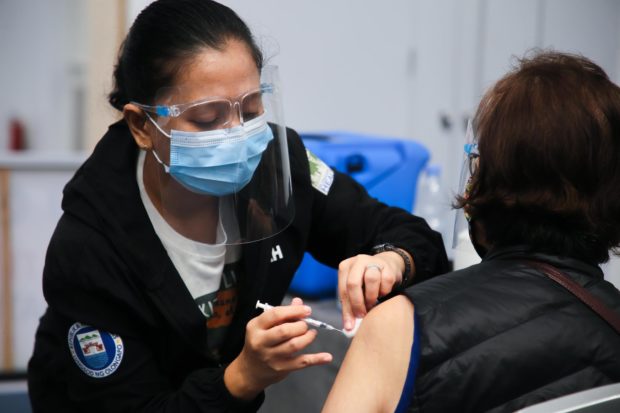 A health worker administers a COVID-19 vaccine to a resident during mass vaccination rollout at the SMX Convention Center in SM Olongapo Central