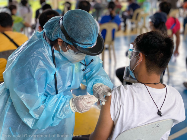 A health worker in Ilocos Norte province administers a COVID-19 vaccine to a resident