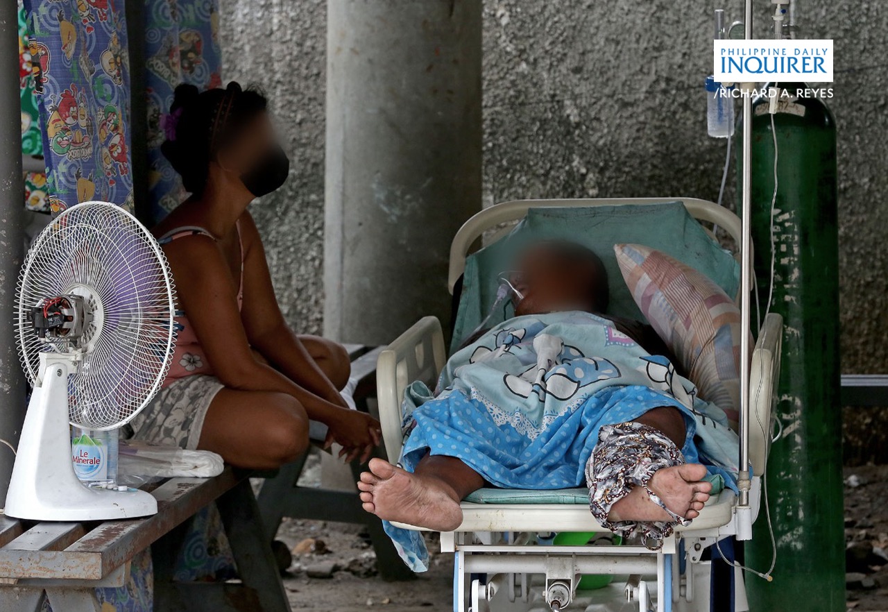 A relative wails over the death of his loved one while being treated in the parking lot of Ospital ng Binan in Laguna province on August 14, 2021 as the hospital hit full bed capacity amid increasing COVID-19 cases. According to medical workers, family members brought the man there earlier that day, coughing and having breathing difficulties after being sick at home for about two weeks. The parking lot was recently converted into a makeshift reception area for patients suspected to be with COVID-19 infection. The Malacañang announced the extension of the ECQ in Laguna to Aug. 20. RICHARD A. REYES / INQUIRER