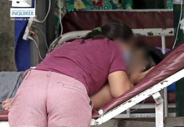 A relative wails over the death of his loved one while being treated in the parking lot of Ospital ng Binan in Laguna province on August 14, 2021 as the hospital hit full bed capacity amid increasing COVID-19 cases. According to medical workers, family members brought the man there earlier that day, coughing and having breathing difficulties after being sick at home for about two weeks. The parking lot was recently converted into a makeshift reception area for patients suspected to be with COVID-19 infection. The Malacañang announced the extension of the ECQ in Laguna to Aug. 20. RICHARD A. REYES / INQUIRER
