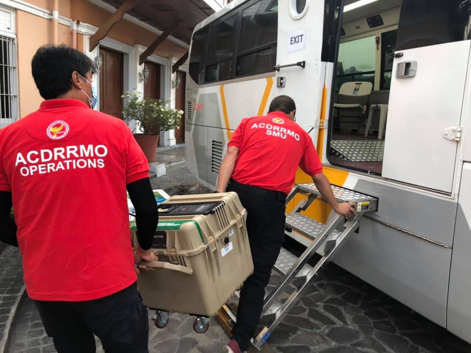 Angeles City government employees load vaccines into a mobile bus clinic