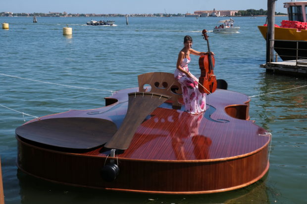A boat in the shape of a giant violin, built as an homage to people who have died from COVID-19, had a test voyage in Venice on Friday as a cellist played on the deck.