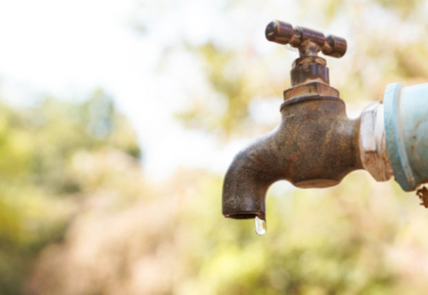 Closeup of faucet with hanging drop of water