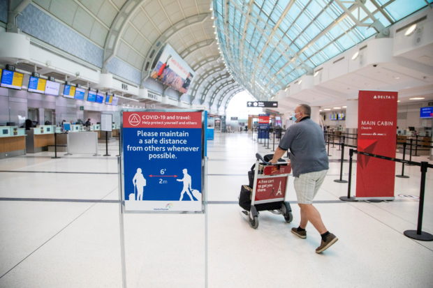 A man pushes a baggage cart wearing a mandatory face mask as a "Healthy Airport" initiative is launched for travel, taking into account social distancing protocols to slow the spread of the coronavirus disease (COVID-19) at Toronto Pearson International Airport in Toronto, Ontario, Canada June 23, 2020.  