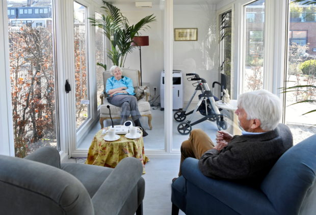 A man visits his wife at a care facility for elderly people with dementia in a glass house that has been built to combat loneliness after a visit ban was imposed due to the coronavirus disease (COVID-19) outbreak in Wassenaar, Netherlands, April 9, 2020. REUTERS/Piroschka van de Wouw/File Photo