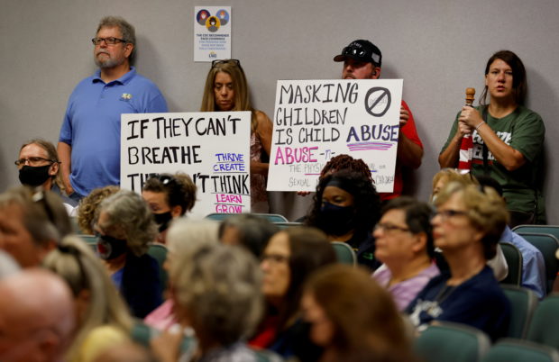 FILE PHOTO: People hold placards as members of the Lake County School Board conduct an emergency meeting to discuss mask mandates to prevent the spread of coronavirus disease (COVID-19) in Tavares