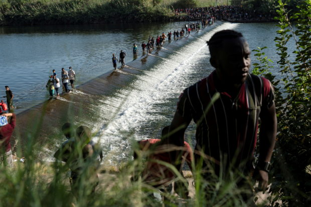 Migrants seeking asylum in the U.S. walk in the Rio Grande river near the International Bridge between Mexico and the U.S., as they wait to be processed, in Ciudad Acuna, Mexico, September 16, 2021. According to officials, some migrants cross back and forth into Mexico to buy food and supplies. REUTERS/Go Nakamura