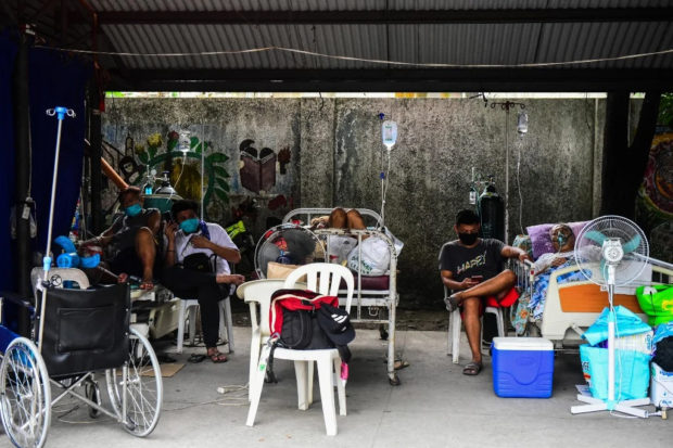 Suspected Covid-19 patients and relatives rest in a parking lot turned into a covid ward outside a hospital in Binan, Laguna